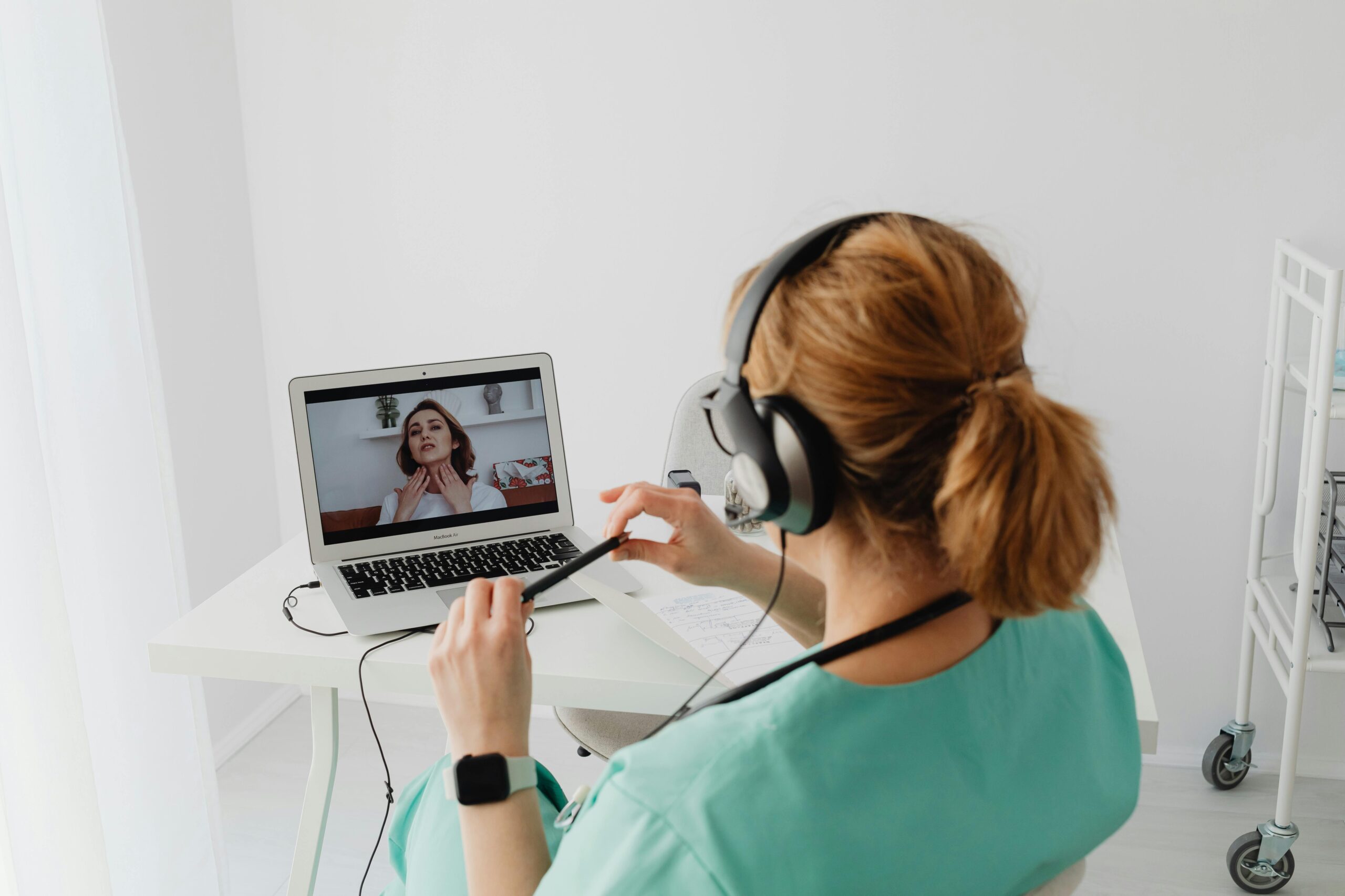 Telehealth Is Here to Stay — And Integrating It Into Your EMR Just Makes Sense A doctor conducting an online consultation with a patient via laptop in a modern office setting.